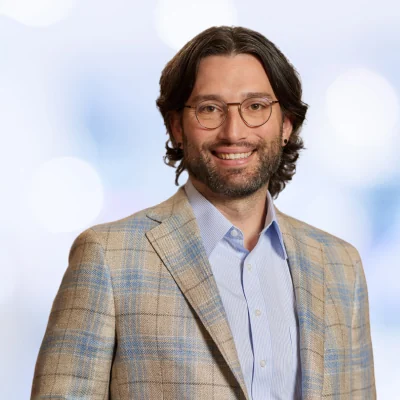 Grant Drawve, smiling, in glasses and a plaid jacket