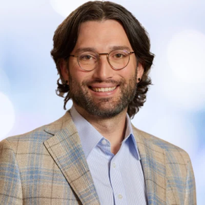 Grant Drawve, smiling, in glasses and a plaid jacket
